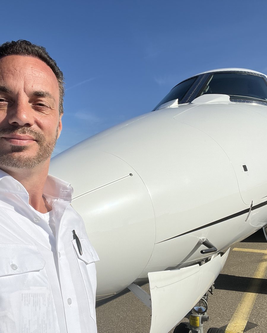 Fabian Voncken, airline pilot, in uniform shirt in front of a Falcon 2000LX